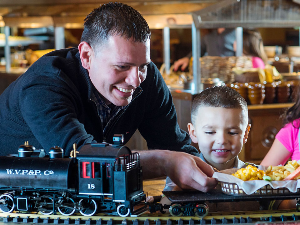 A man helps his son with his train-delivered food at Buffalo Phil's