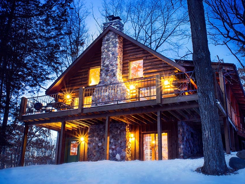 Large cabin looking cozy in a snowy winter evening.