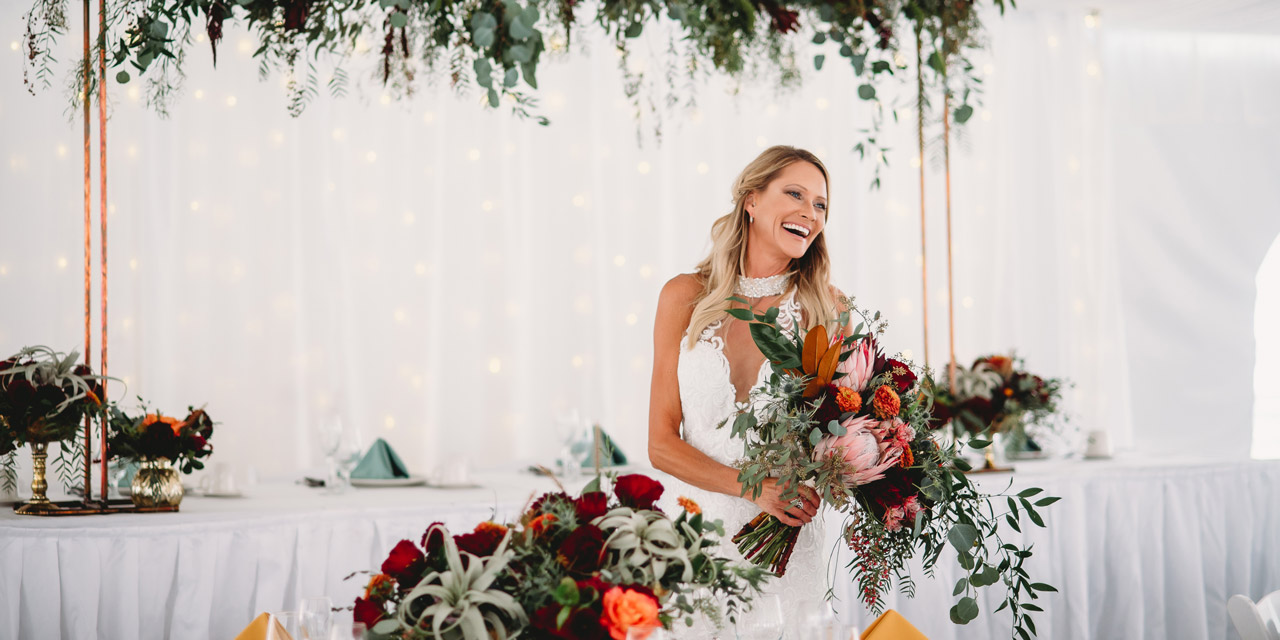 Happy bride inside a decorated wedding venue tent.