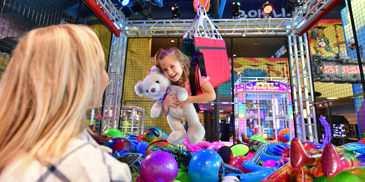 Little girl riding on a human claw machine.