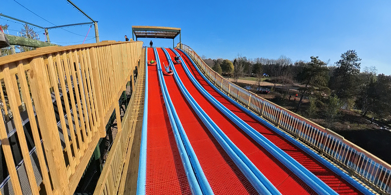 People tubing down a red slide.