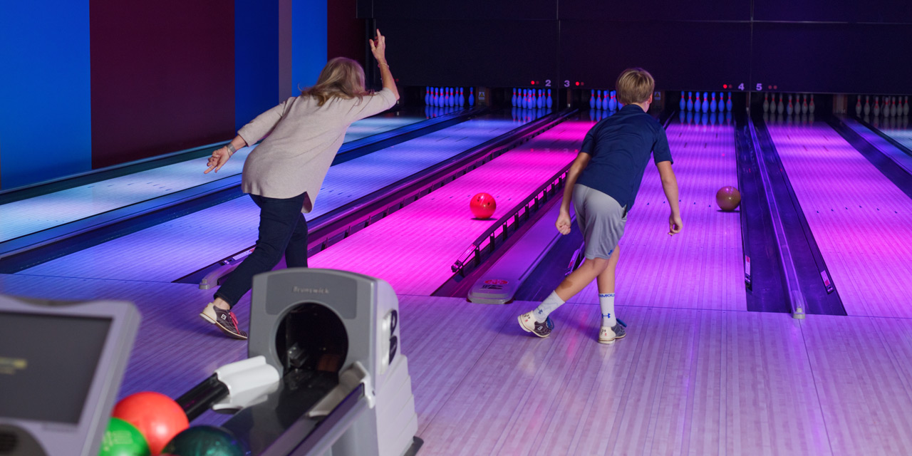 Grandma and grandson bowling in a glow light setting.