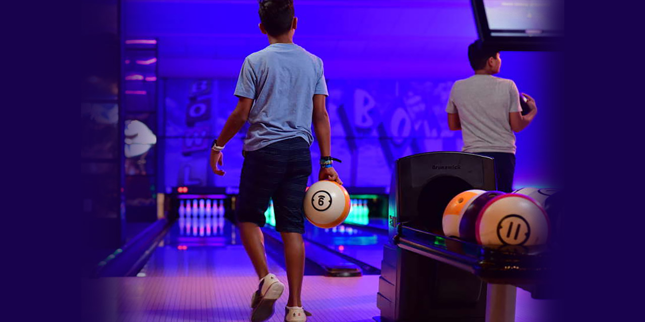 Two kids bowling in a glow light.