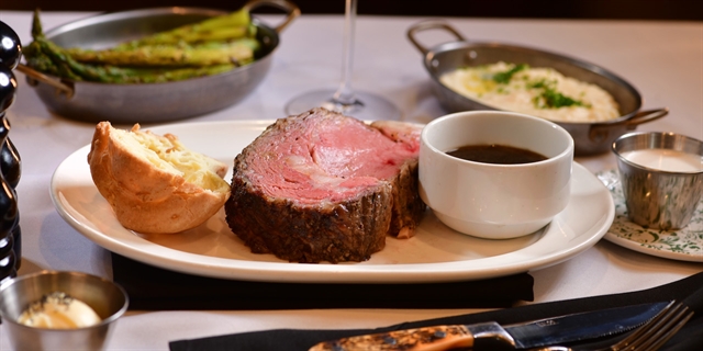 Plated prime rib with au jus and piece of bread.